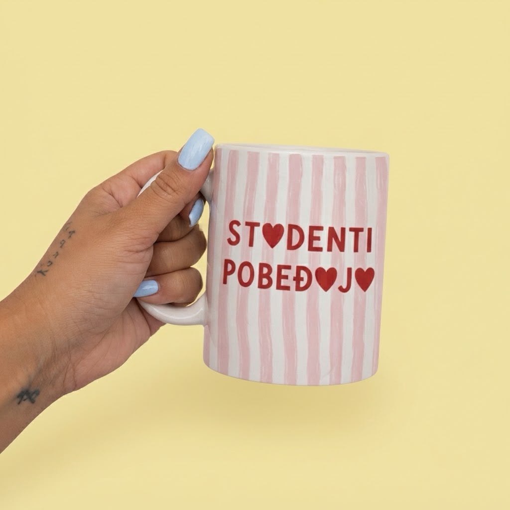 Roze-bela prugasta šoljica sa srcima, natpis Studenti pobeđuju